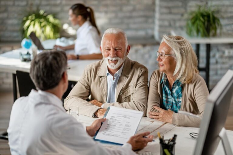 happy-senior-couple-communicating-with-doctor-about-their-health-insurance-while-going-through-paperwork_637285-1194